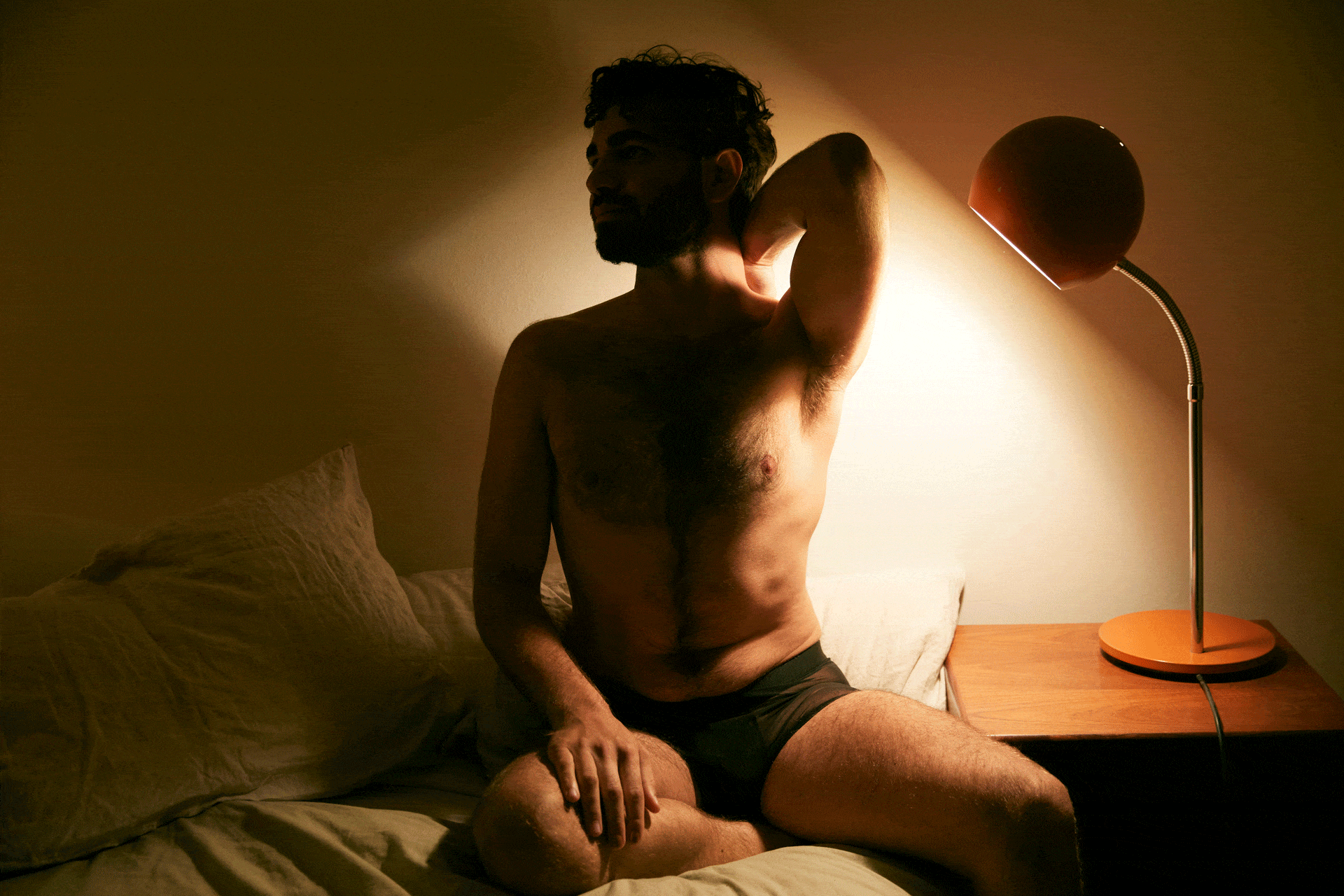 Homme assis sensuellement sur son lit la nuit